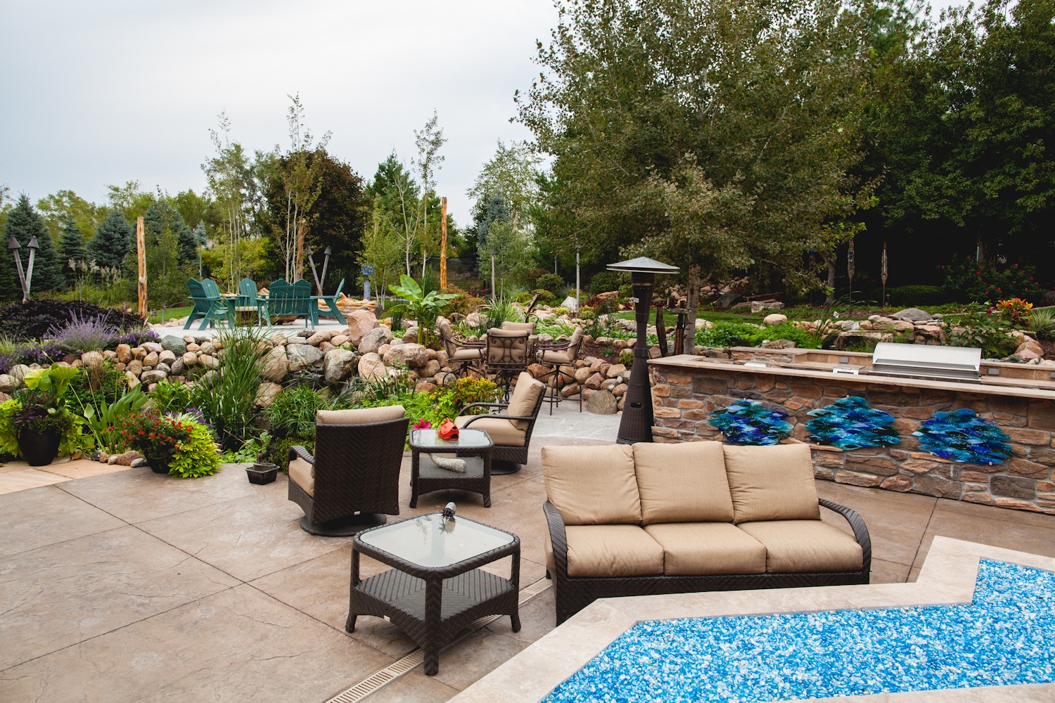 An outdoor patio with furniture, a kitchen, and a blue firepit.