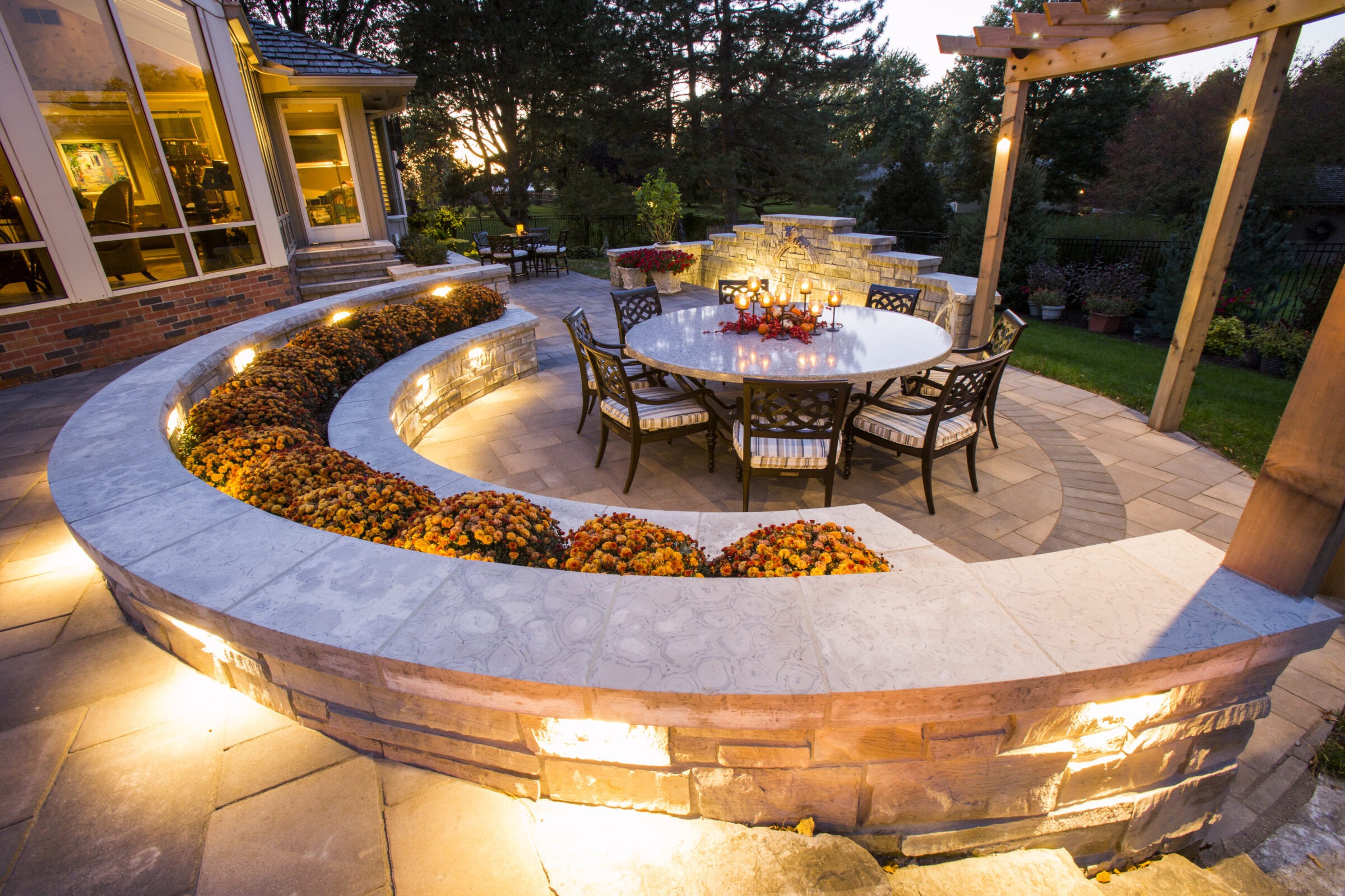 An outdoor stone seating area with lights and a dining table.