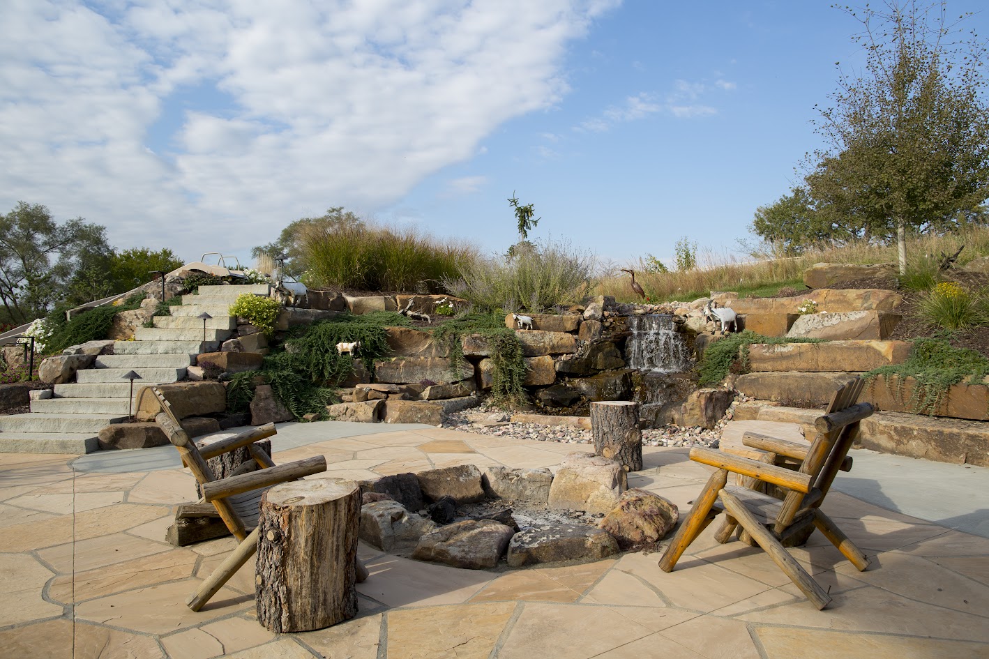 An attractive outdoor space with custom stonework, a firepit, and a waterfall.