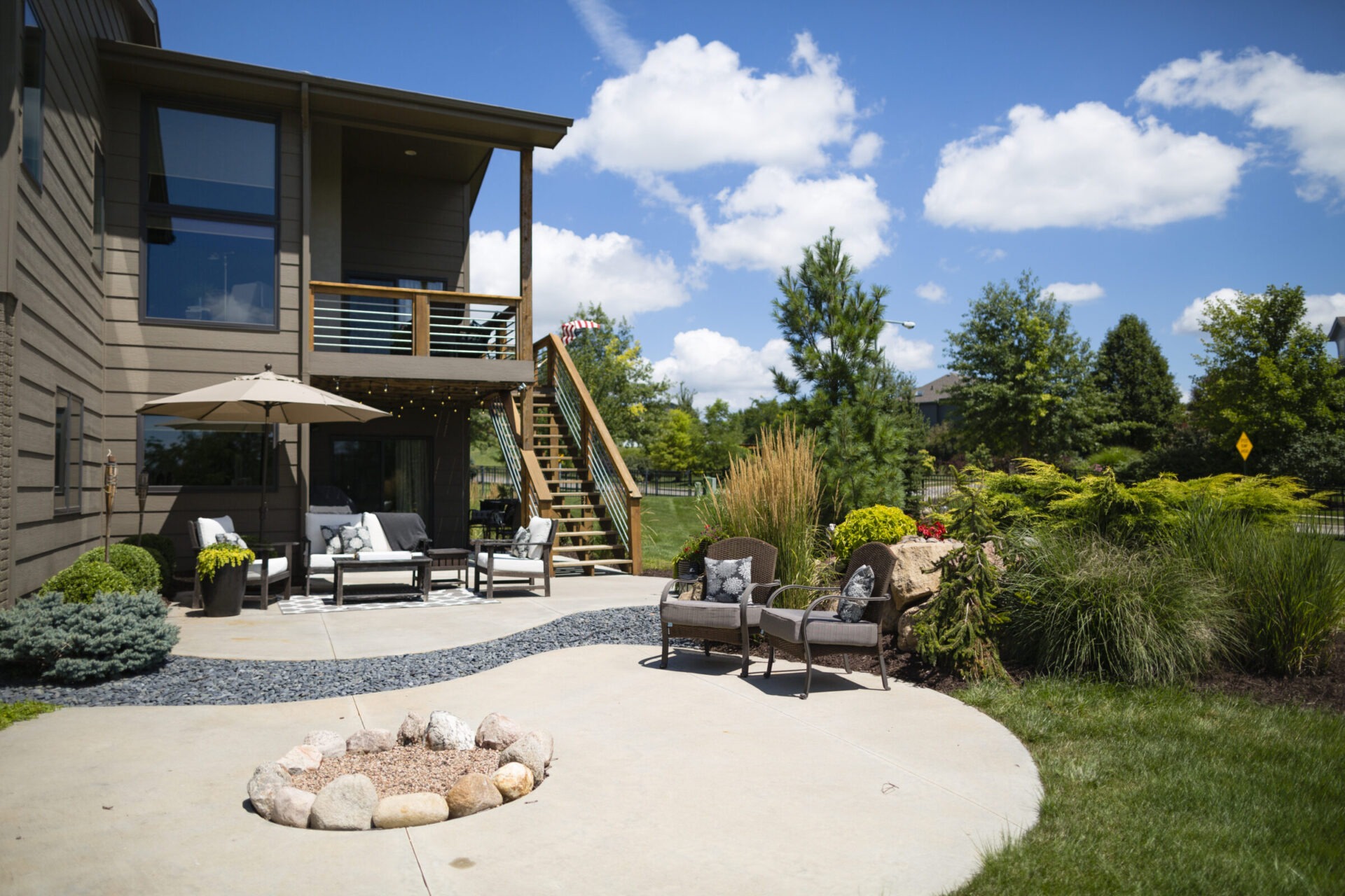 Backyard patio with seating, umbrella, and landscaping.