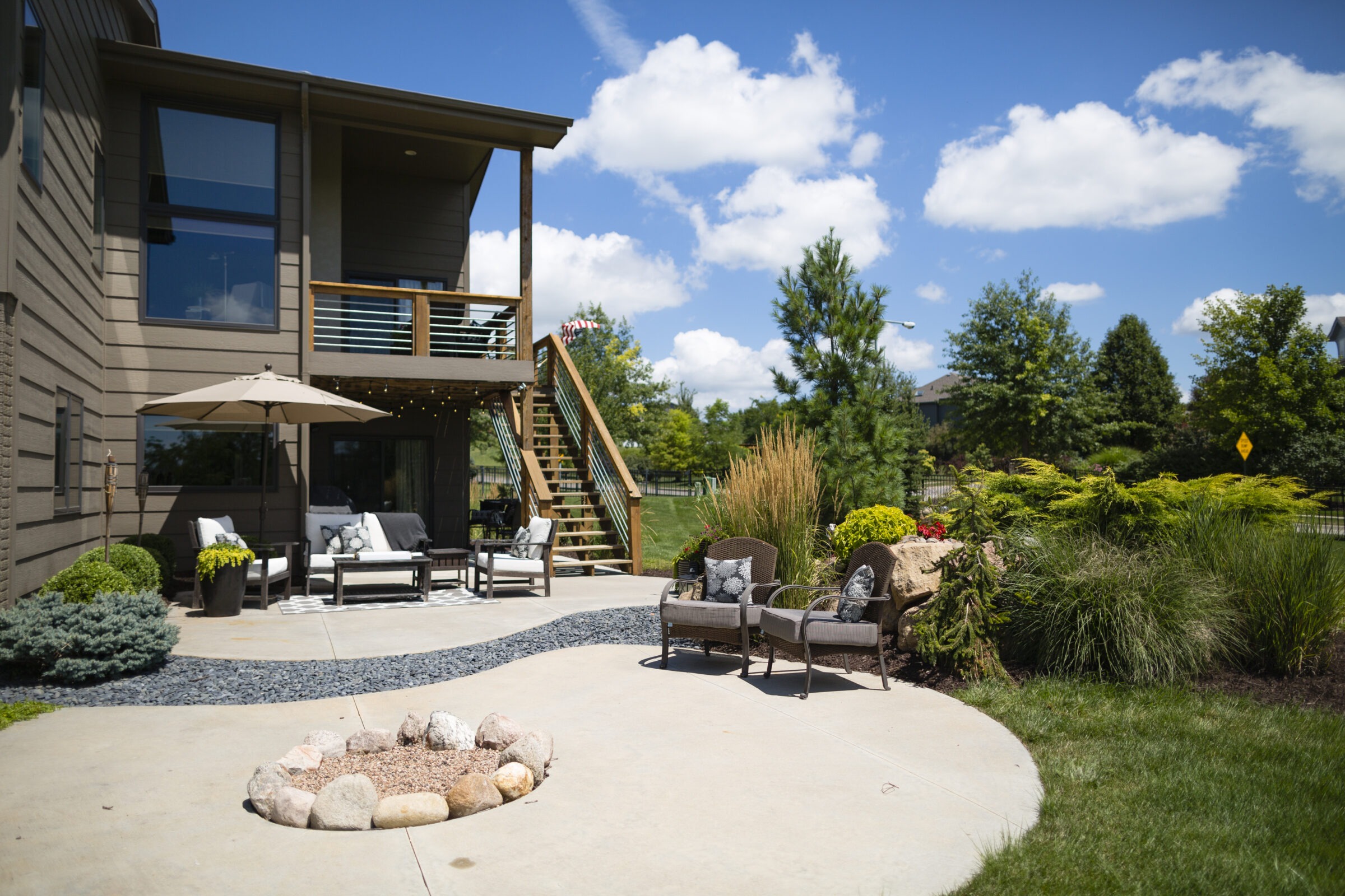 Backyard patio with seating, umbrella, and landscaping.