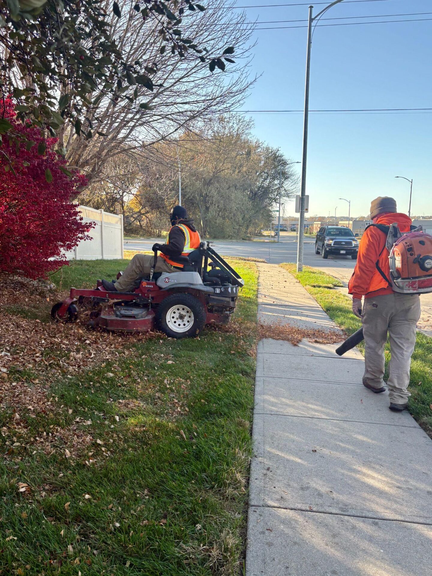 Landscaping crew performing fall clean-up with mower and leaf blower.
