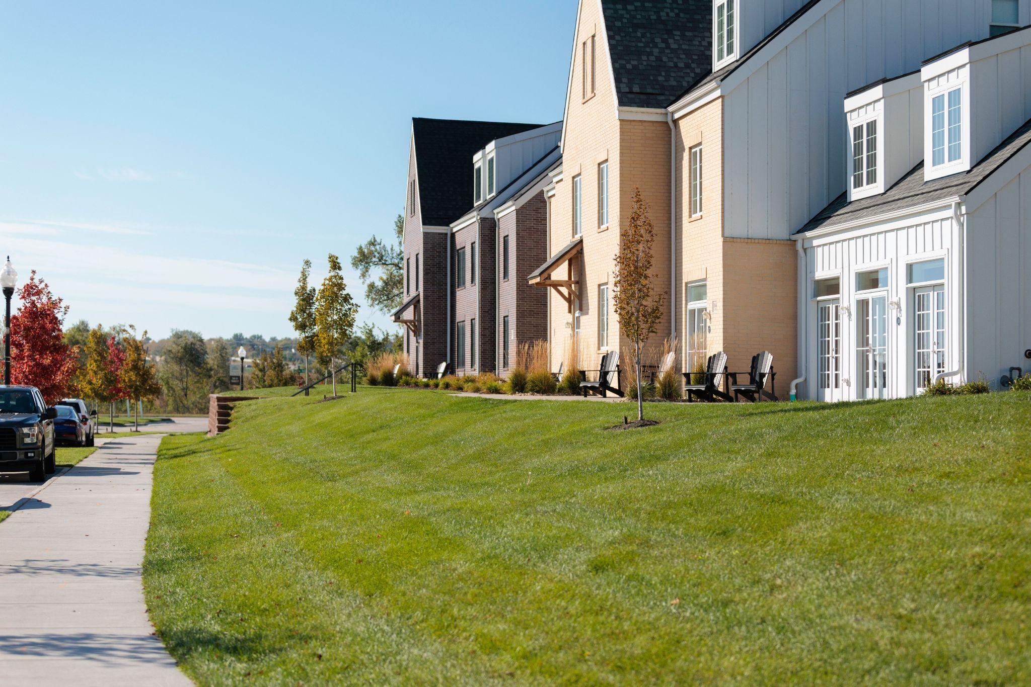 Row of townhomes with sloped, well-maintained front lawns.