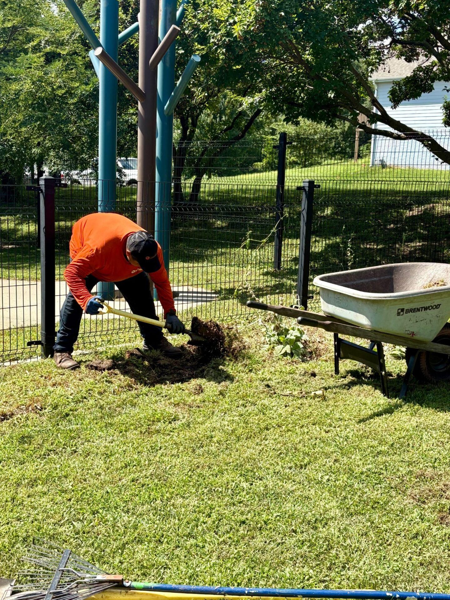 Worker digging out turf for maintenance near a decorative pole.