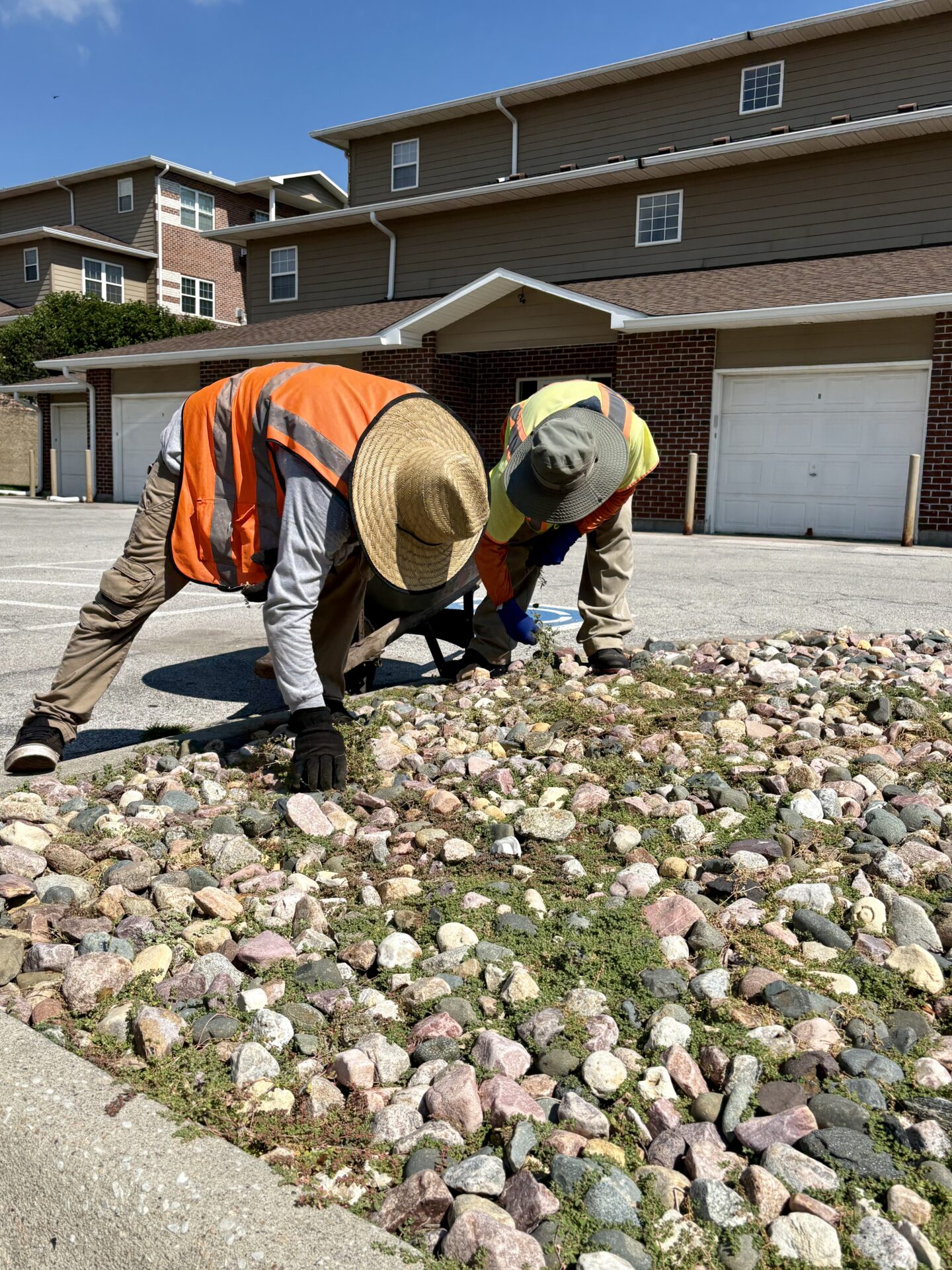 Two men doing landscaping in front of a parking garage