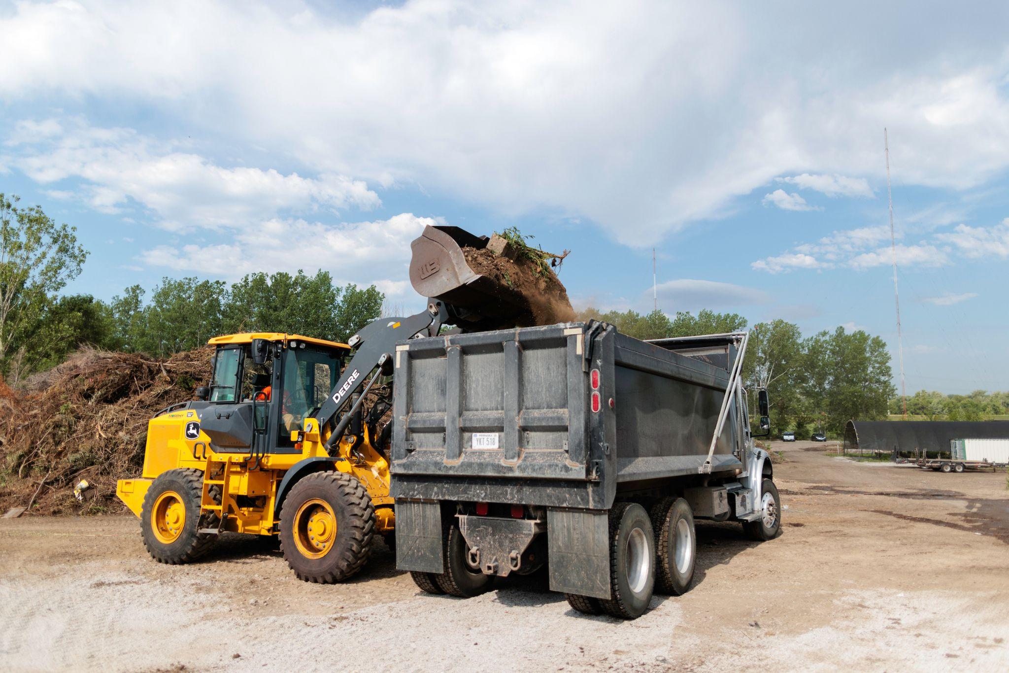 wheel loader loading debris into a dump truck at a landscape yard